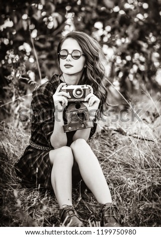 Beautiful girl in plaid dress retro camera and sunglasses at countryside. Image in black and white color style