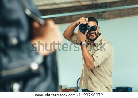Photographer doing a photo shoot in a studio. Blurred close up of model posing for  photograph.
