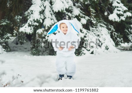 Portraita little boy dressed as rabbit in winter forest. Child with christmas wreath. Snowy park.