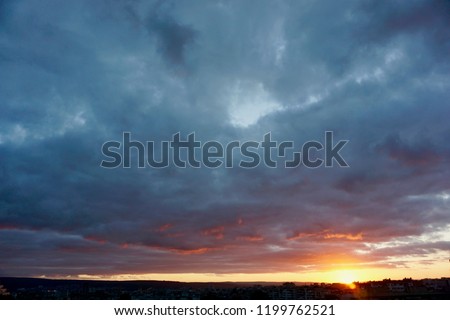 Velvet sky at sunset. Clouds in amazing colours. Clouds soft as cotton. Orange sun falling behind the black horizon under a dramatic sky. Nature background.             