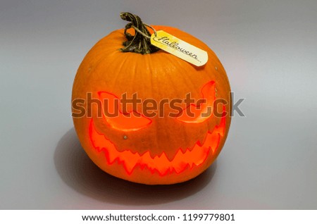 Jack o lantern with red light and label on grey background. Halloween decor.