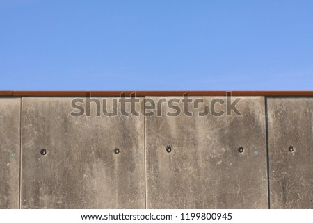 Border or prison cement gray concrete wall against a blue sky - close up with copy space
