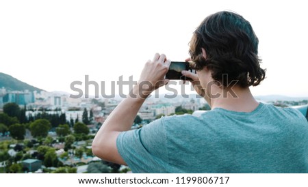 Tourist is taking pictures of a historical place in the city from a viewing platform on the smartphone.