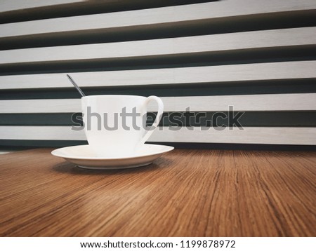 Coffee cup on wooden table background. A white coffee cup on wooden table. Cup of cappuccino with latte art on wooden background.