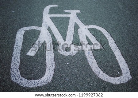 White bicycle sign painted on grey tarmac