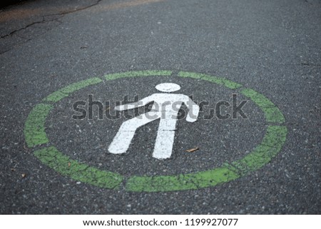 Green pedestrian lane sign on dark wet asphalt