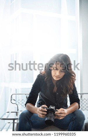 young hipster woman photographer  holding camera near the window.