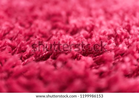 The texture of the pile of the carpet close-up. Abstract background of the pile of the carpet with a selective focus. Macro picture of a red rug.