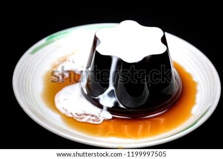 Coffee Jelly With Condensed Milk And Syrup Isolated On Round White Plate Against Black Background