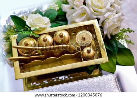 A gold tepak sireh as malay traditional container with betel leaves sat on white and pink roses for wedding or gift Royalty-Free Stock Photo #1200045076