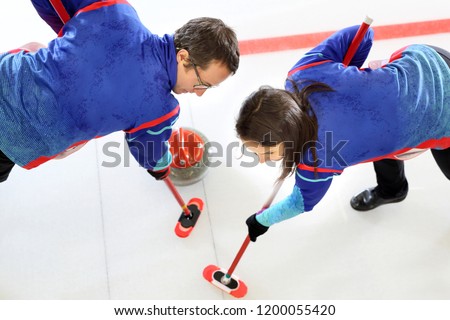 Curling games. The player is brushing the ice by directing the stone to the house Royalty-Free Stock Photo #1200055420