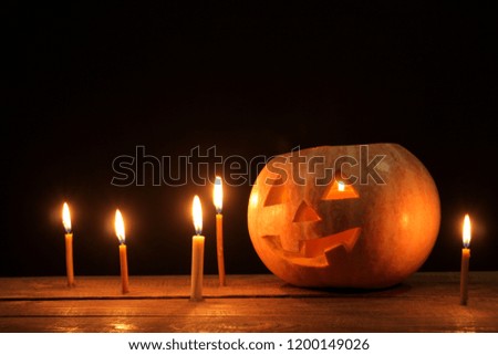 The concept of the holiday of Halloween. Halloween pumpkin head with candles inside and around on a wooden table on a black background