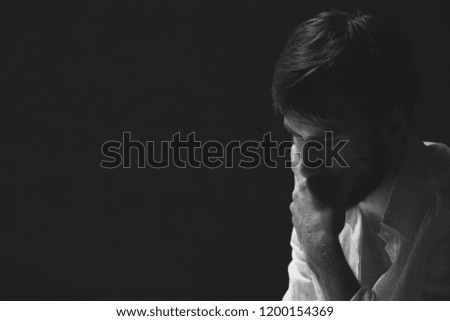 Black and white portrait of handsome worried man, photo with copy space on dark background