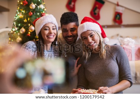 Young happy friends celebrating new year and christmas together. Taking a picture of this beautiful moment.