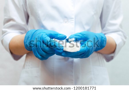 Syringe with a blue medical drug and a bandage in the doctor hands dressed in the medical gown.