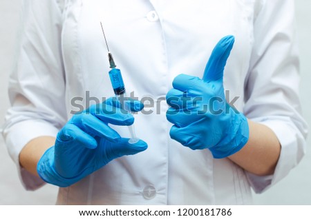 Syringe with a blue medical drug and doctor hand which showing a thumbs up sign. The best medical drug concept.