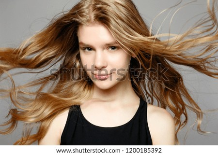 Attractive young girl touching her face. Photo of blonde girl with perfect skin on grey background. Beauty and Skin care concept. Beautiful young woman with natural makeup and clean skin