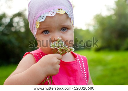 little girl holding bunch of clover outdoors and looking at camera