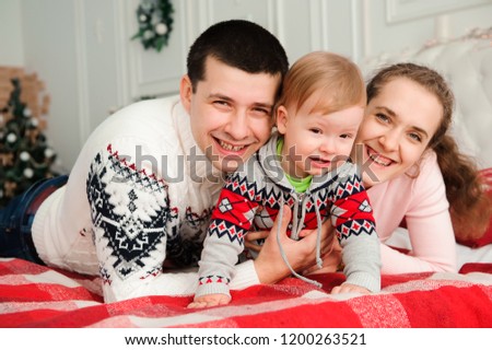 Happy smiling family with one year son near the Christmas background