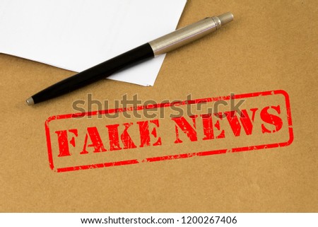  Pen on brown paper envelope with fake news stamped.