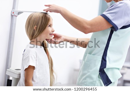 Picture of female doctor measuring height of girl in clinic