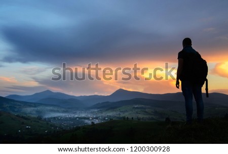 A traveler-photographer observes the sunset over the forest and mountains in the Ukrainian Carpathians