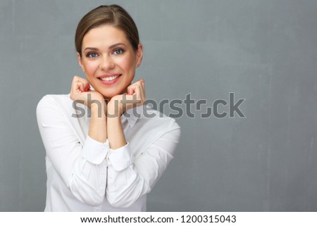Close up portrait of smiling woman wearing white shirt touching her face with hands.