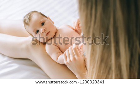 selective focus of little baby on mother knees in bed at home 