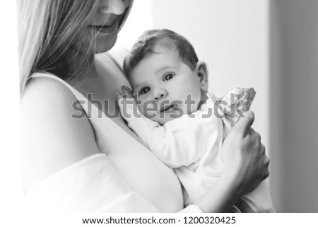 black and white picture of mother carrying little baby boy at home