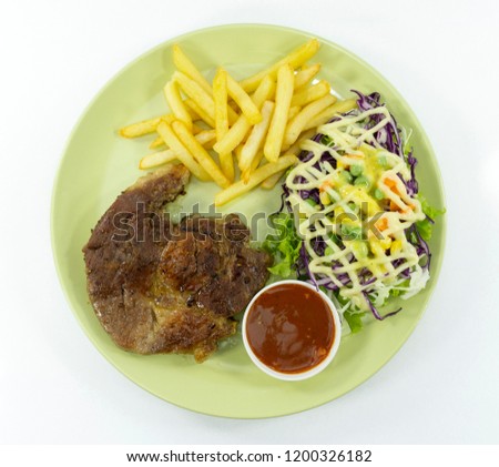Steak Kurobuta pork chop black pepper sauce in plate on white background. props decoration French fries, green salad,Top view.