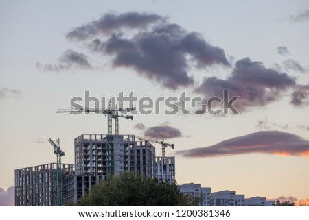 Construction site with cranes on the evening sky background