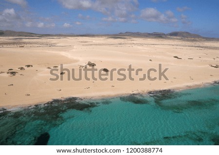 Aerial photography of the landscape of dunes and emerald waters on the coast of Corralejo north of Fuerteventura, Canary Islands
