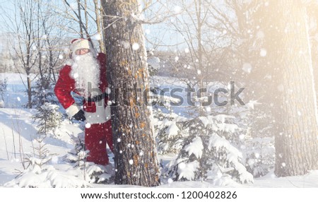 Santa Claus comes with gifts from the outside. Santa in a red suit with a beard and wearing glasses is walking along the road to Christmas. Father Christmas brings gifts to children.
