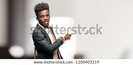 young black businessman smiling and pointing upwards with both hands, towards the place where the publicist may show a concept.