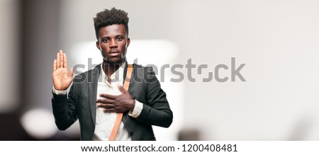 young black businessman smiling confidently while making a sincere promise or oath, solemnly swearing with one hand over heart.