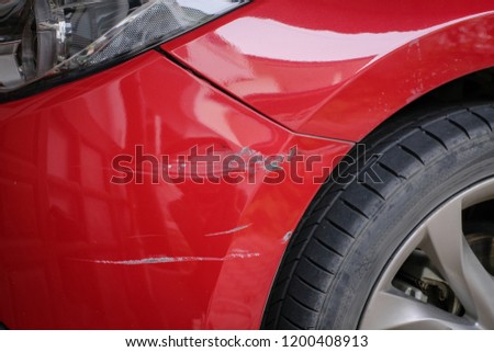 red bumper car scratched with deep damage to the paint, accident concept. Royalty-Free Stock Photo #1200408913