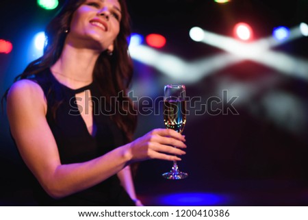 holidays, nightlife, drinks, people and luxury concept - beautiful young woman drinking champagne at party over lights background.