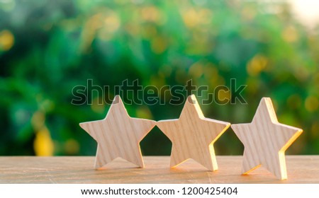 Three wooden stars on a green bokeh background. The concept of the rating of hotels and restaurants, the evaluation of critics and visitors. Quality level, good service. selective focus
