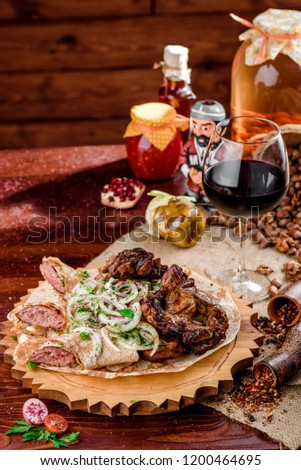 Georgian cuisine. grilled meat with onions, pita bread with sausages and a glass of rad wine on a wooden board in a beautiful composition on a burlap on a wooden table. close-up.