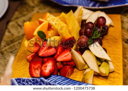 Variety of fruits on a yellow tray in restaurant, topview
