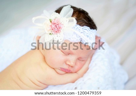 Sweet and innocent Caucasian infant girl sleeping on a soft blanket, flower head band on her head.