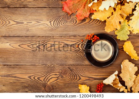 Autumn, fall leaves, hot steaming cup of coffee and on wooden table background. Seasonal, morning coffee, Sunday relaxing and still life concept.