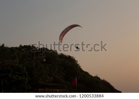 background desktop theme alone skyglider sportsman skygliding red parachute high in  sky contrast silhouette  in action full of adrenaline above palm trees on travel sport leisure holiday in Goa India