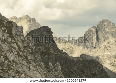 rocky sharp mountain tops in Tatra mountains in Slovakia with clouds and mist from above and rain clouds. Rysy mountain. - vintage retro look