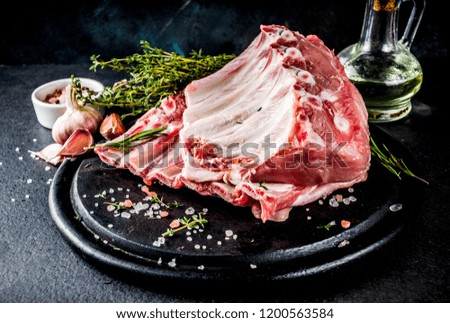 Raw meat, pork ribs with herbs and spices, black stone background copy space