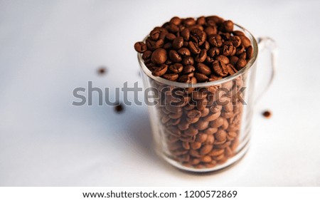Lots of coffee beans in a clear mug. Fresh coffee concept