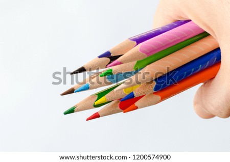 Colored pencils in hand  on white background.