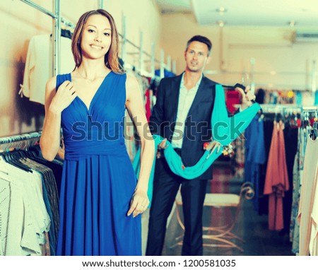 Female 25-30 years old is trying on new dark blue dress in boutique. 
