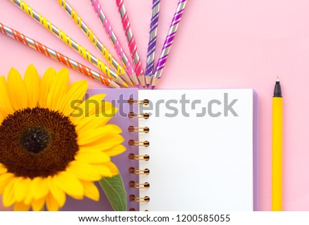 Top view flat lay picture with notepad as mockup for your design and flower on pink background. Copyspace for your text.