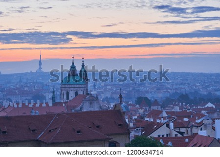  Cityscape of landscape Picture of the lesser town with dome of Saint Nicolas church in the Prague, in the morning just before sunrise in blue mood with orange sky.                              